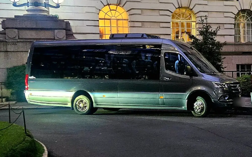 Grey Mercedes 22-seat executive minibus with tinted windows outside a London hotel