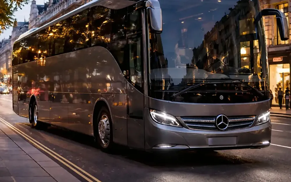 Silver-grey 55-seat luxury coach on a London street at dusk